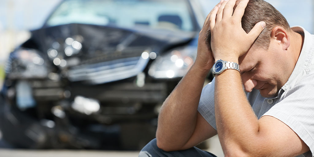 Upset man in front of his wrecked card