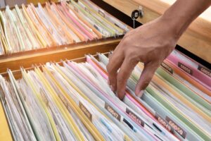 Close-up of a hand searching through detail medical files for a car accident injury claim.