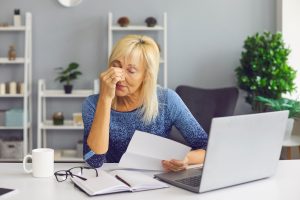 Stressed woman reviewing documents at her desk, representing the difficulties of appealing a denied SSD claim