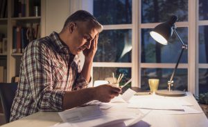 Stressed man reviewing financial documents related to lost wages after a car accident.